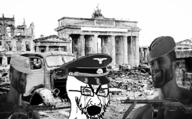 angry berlin bloodshot_eyes brandenburg_gate cap clothes crying destruction germany gigachad glasses gun hat irl nazism open_mouth soviet_union soyjak stubble variant:cryboy_soyjak // 1024x634 // 973.5KB